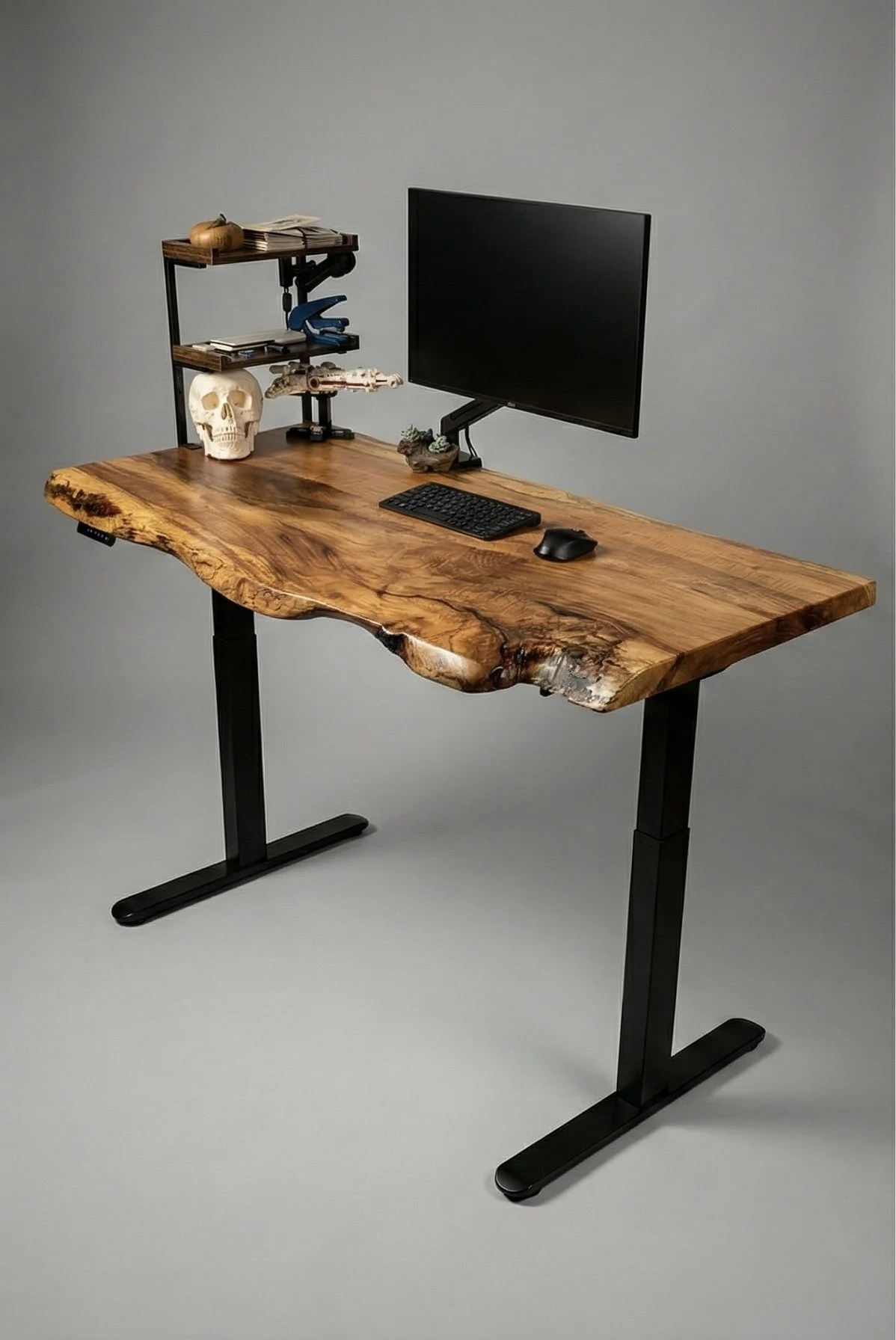 A wooden desk with a computer monitor, keyboard, and mouse, alongside decorative items such as a skull, model spaceship, and a small plant, against a plain background.