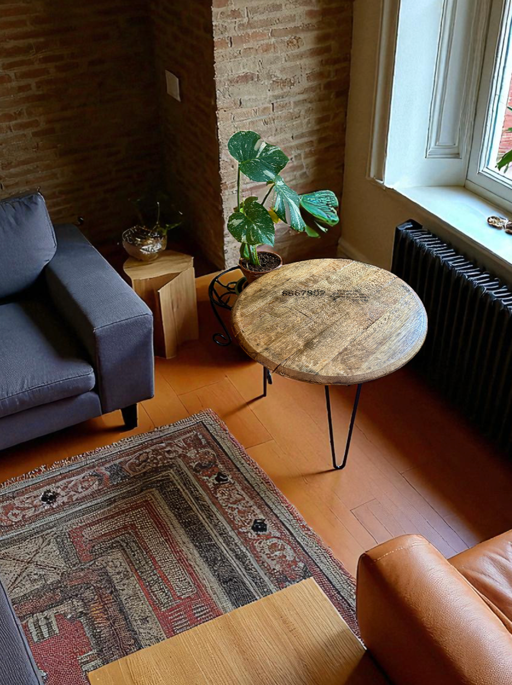 A cozy living room corner with a gray sofa, a small wooden side table with a glass bowl plant, a large potted plant on a metal stand, a round wooden table with black metal legs, a colorful patterned area rug, and a window with sunlight streaming in.