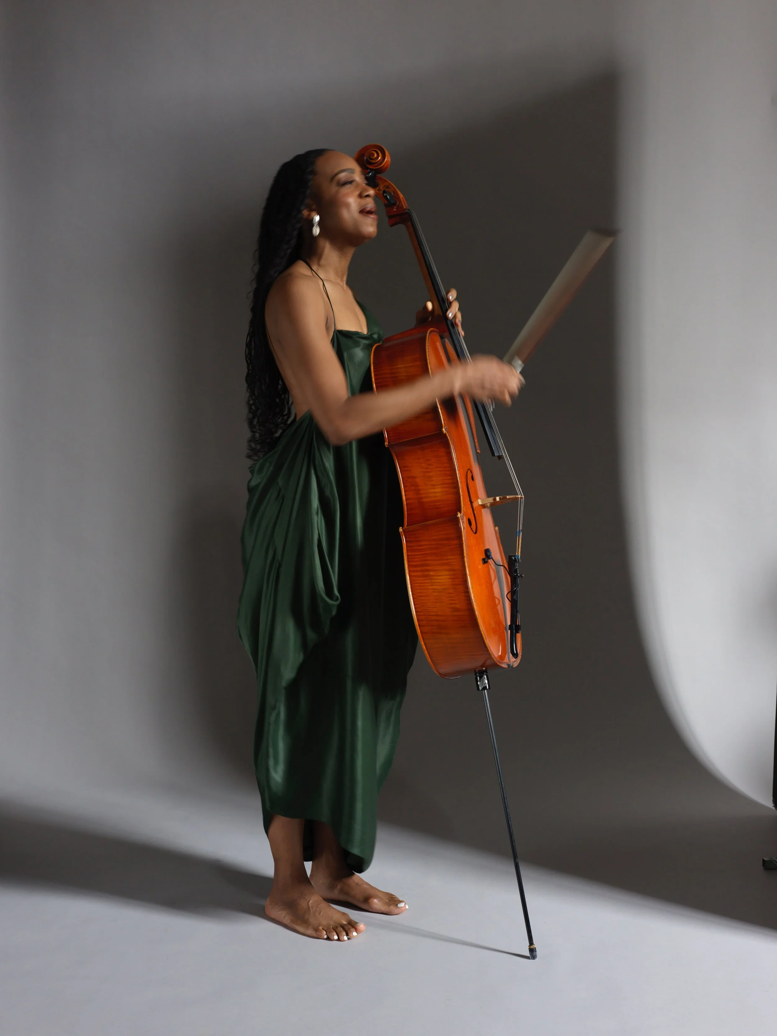 Ayanna Witter-Johnson in green dress on cello blurred with smile