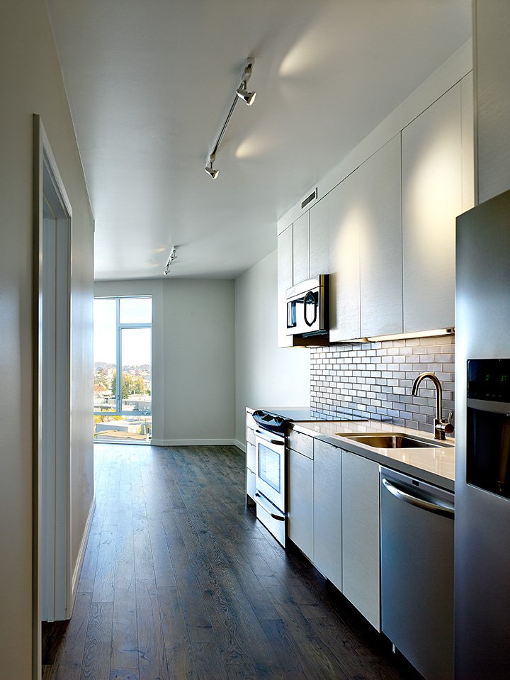 Modern kitchen with white cabinets, black subway tile backsplash, stainless steel appliances, and a large window letting in natural light.