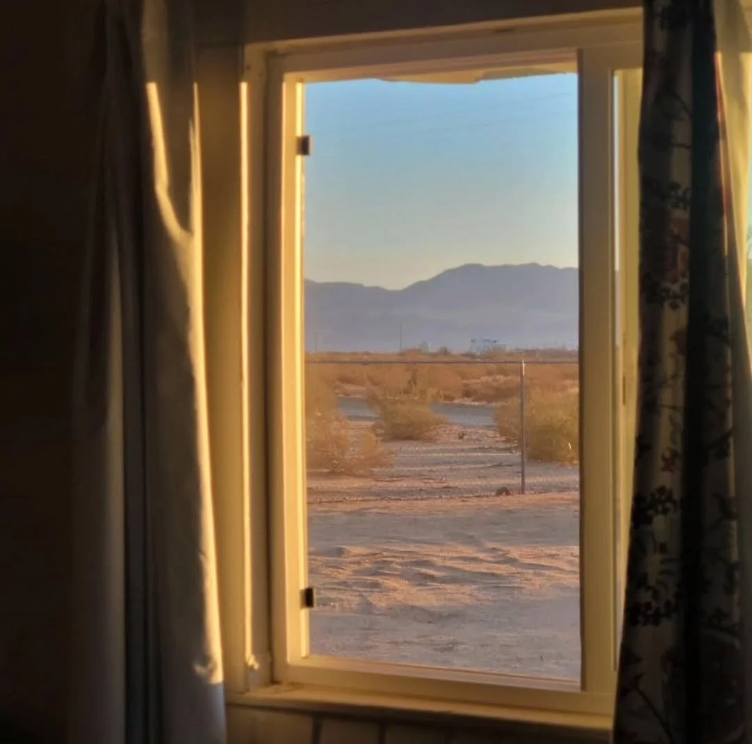 View of the high desert landscape through a window at Kit Fox Cabin in the early morning light near Joshua Tree