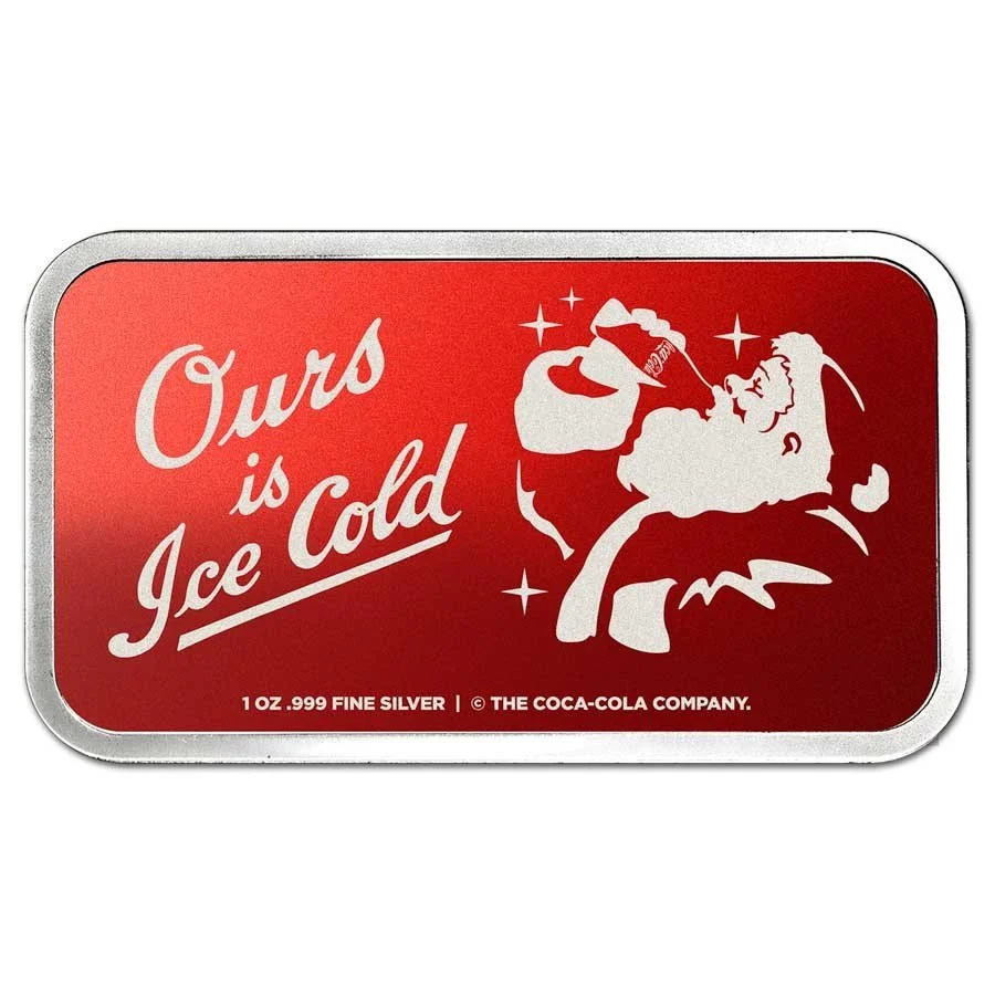 A silver rectangular tin with a red label featuring a stylized Santa Claus drinking from a bottle, with the text "Our is Ice Cold" and small print indicating it contains 1 ounce of 0.999 fine silver, produced by The Coca-Cola Company.