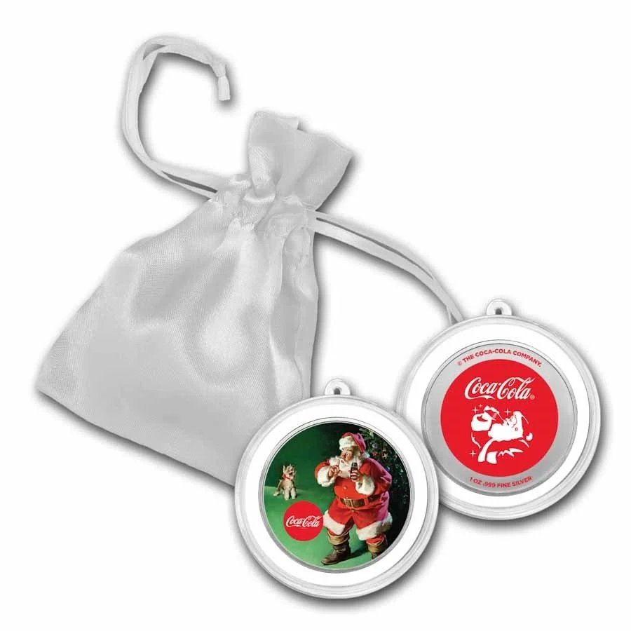 Two rounds of Coca-Cola collectible coins with holiday designs, one featuring Santa Claus with a reindeer and the other with the Coca-Cola logo, attached to a white satin drawstring bag.
