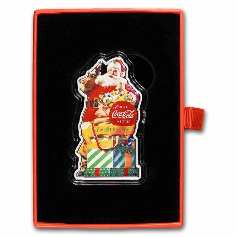 A Coca-Cola gift card featuring Santa Claus holding a bottle of Coca-Cola inside a decorated Christmas scene, with wrapped presents at the bottom, in a red and black box.