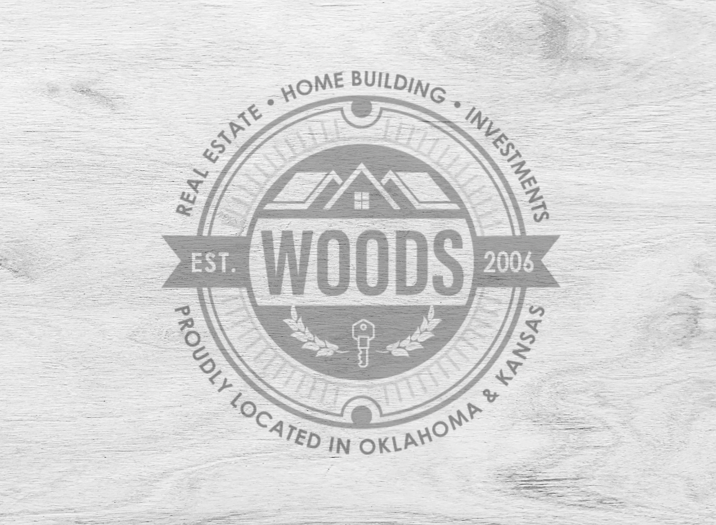 A circular wood grain texture logo with the word 'WOODS' in the center, surrounded by a house graphic with mountains, a key, and laurel branches. The logo includes the text 'Real Estate, Home Building, Investing, Property Located in Oklahoma & Kansas