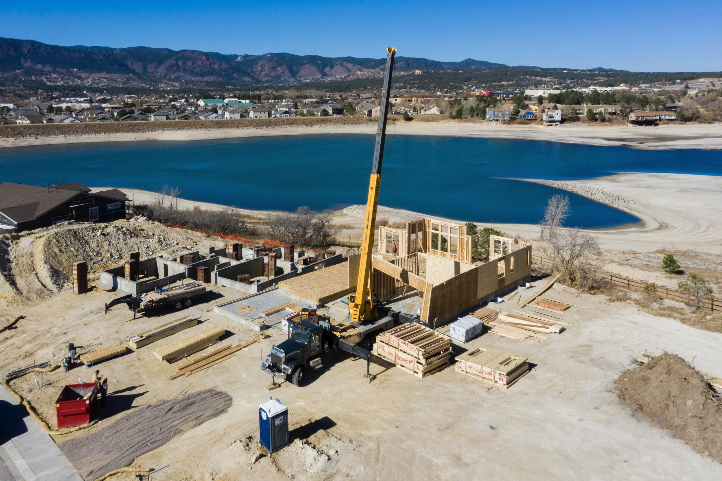 Construction site in Monument Colorado with framing for a house near a lake and mountains in the background.