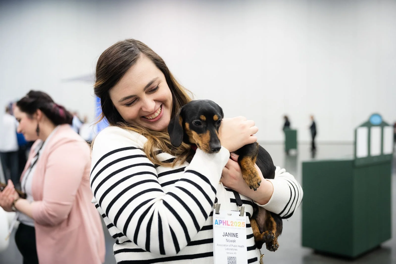 A smiling woman holding a dog at the Portland Expo Center