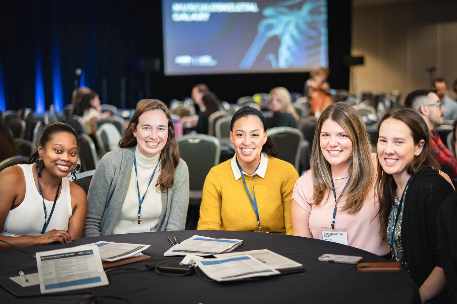 A smiling group of woman at a table in a conference hall