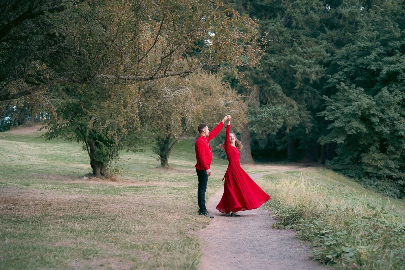 A couple in matching red outfits dance on a path at Mt Tabor