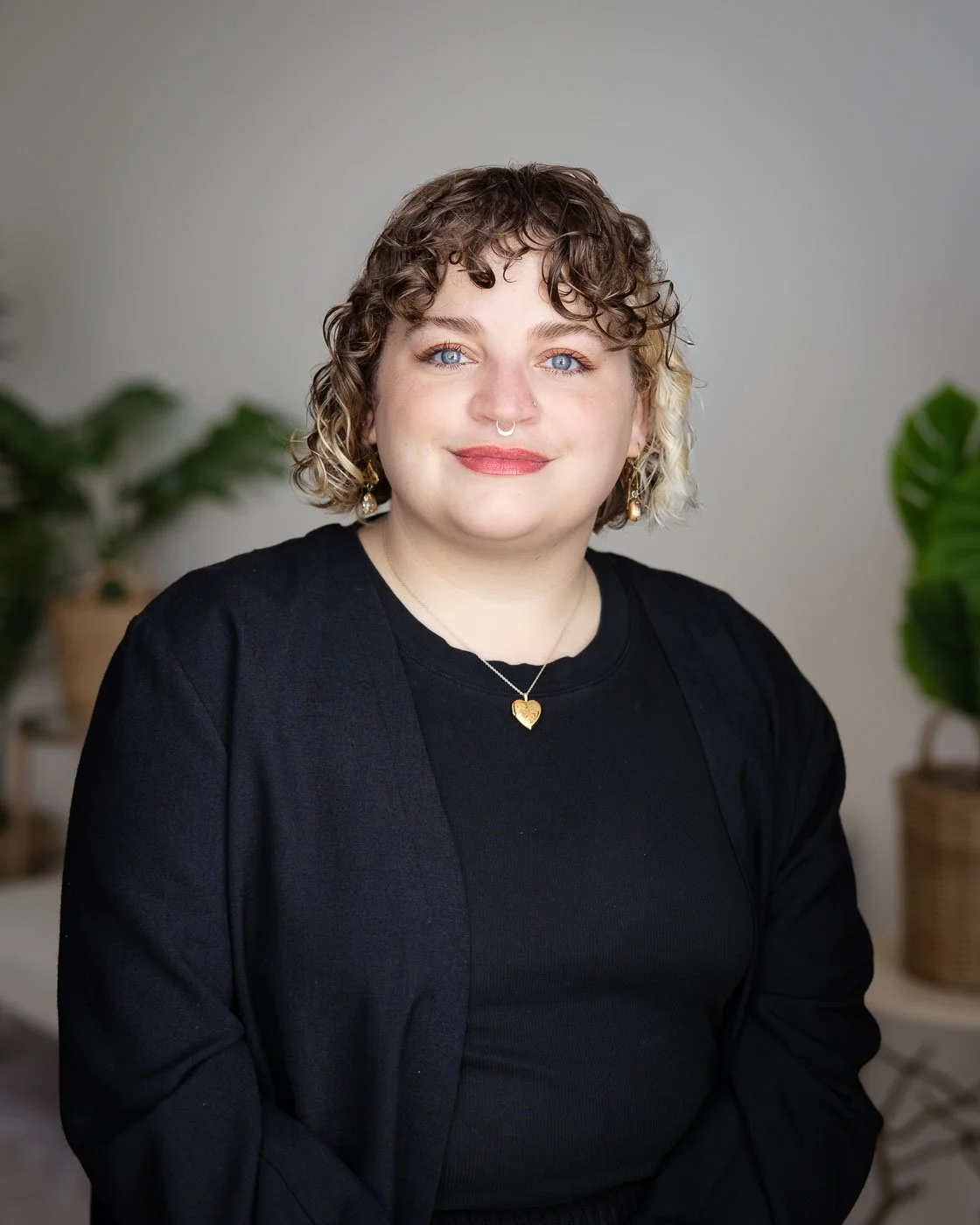 Headshot of a professional woman in a neutral studio space with plants