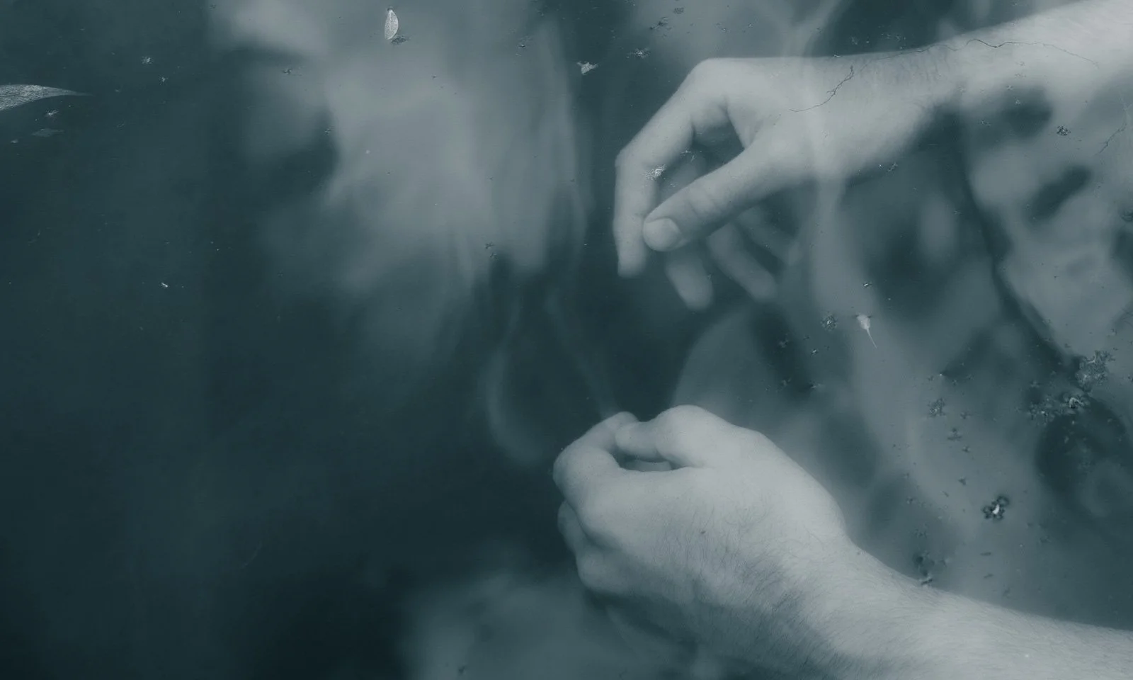 Hands underneath blue water