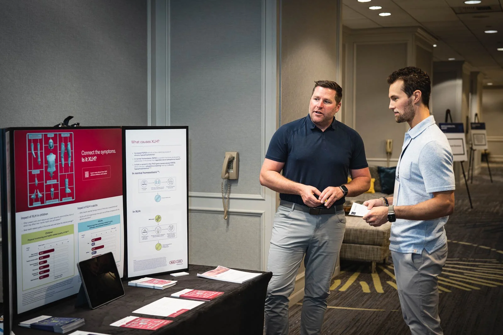 Two men talking in front of a expo booth for at a medical conference
