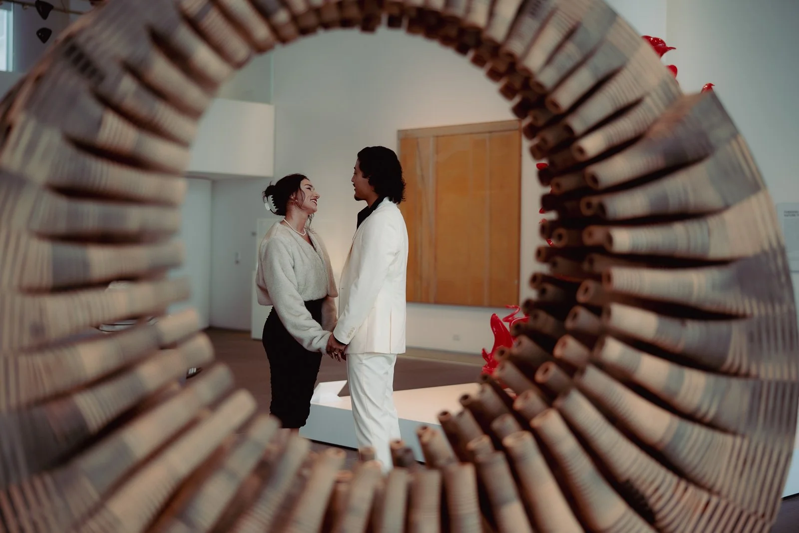  A couple framed by a piece of art holding hands 