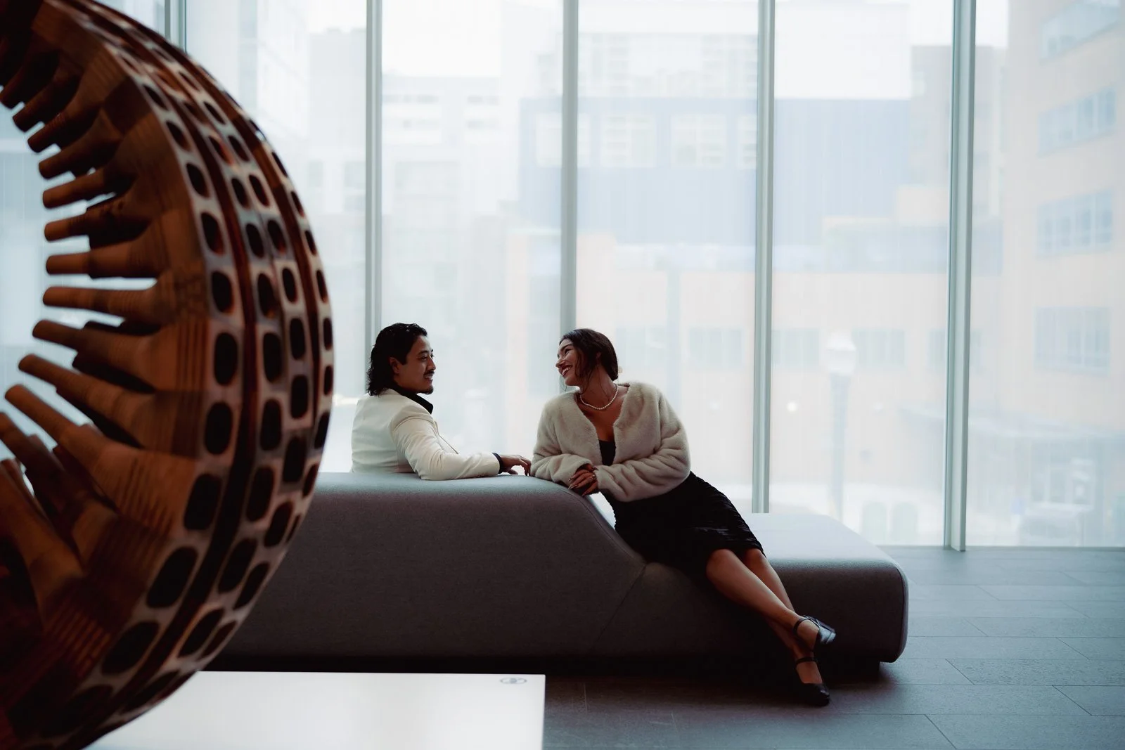  Sitting on a couch in the Portland Art Museum, a laughing couple looking at each other 