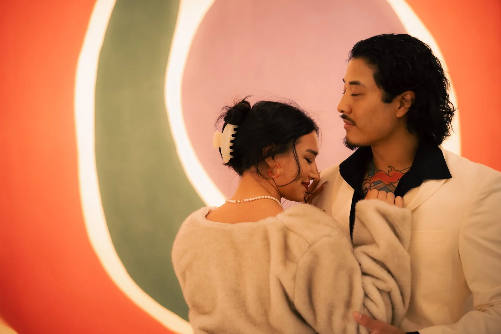  A recently engaged couple holding each other in front of a colorful patterned painting 
