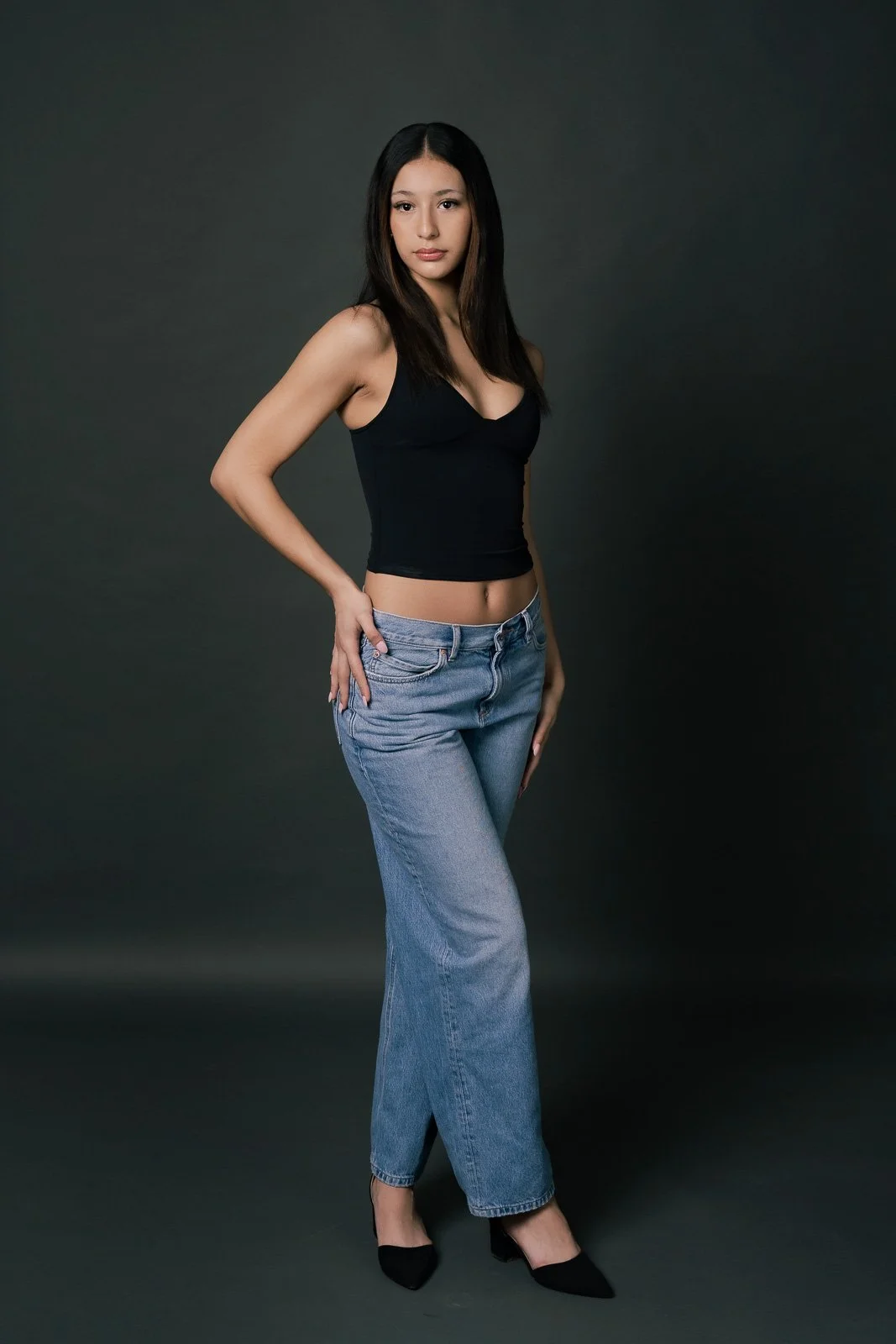 A young girl with dark hair poses for a modeling shoot