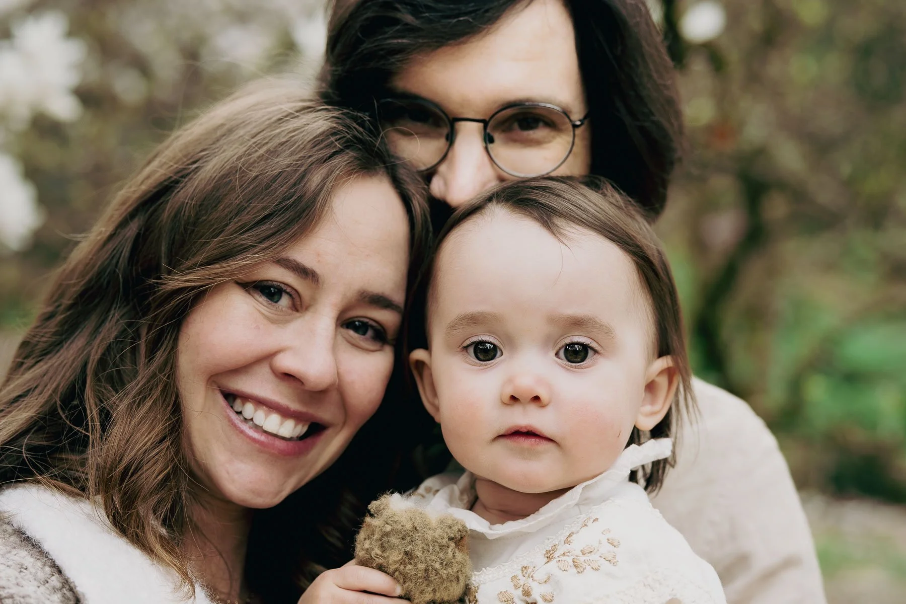 Smiling parents and their child hug each other and squish their faces together