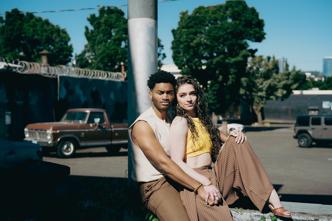 Young couple holding each other in an urban environment with vintage car behind them