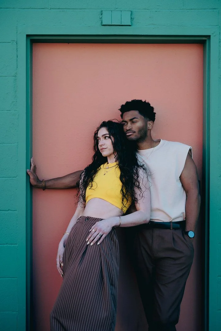 Engaged couple lean in a colorful doorway in downtown Portland