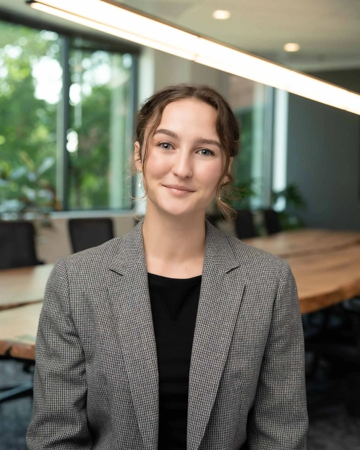  A young smiling female lawyer in a checkered blazer and black shirt 