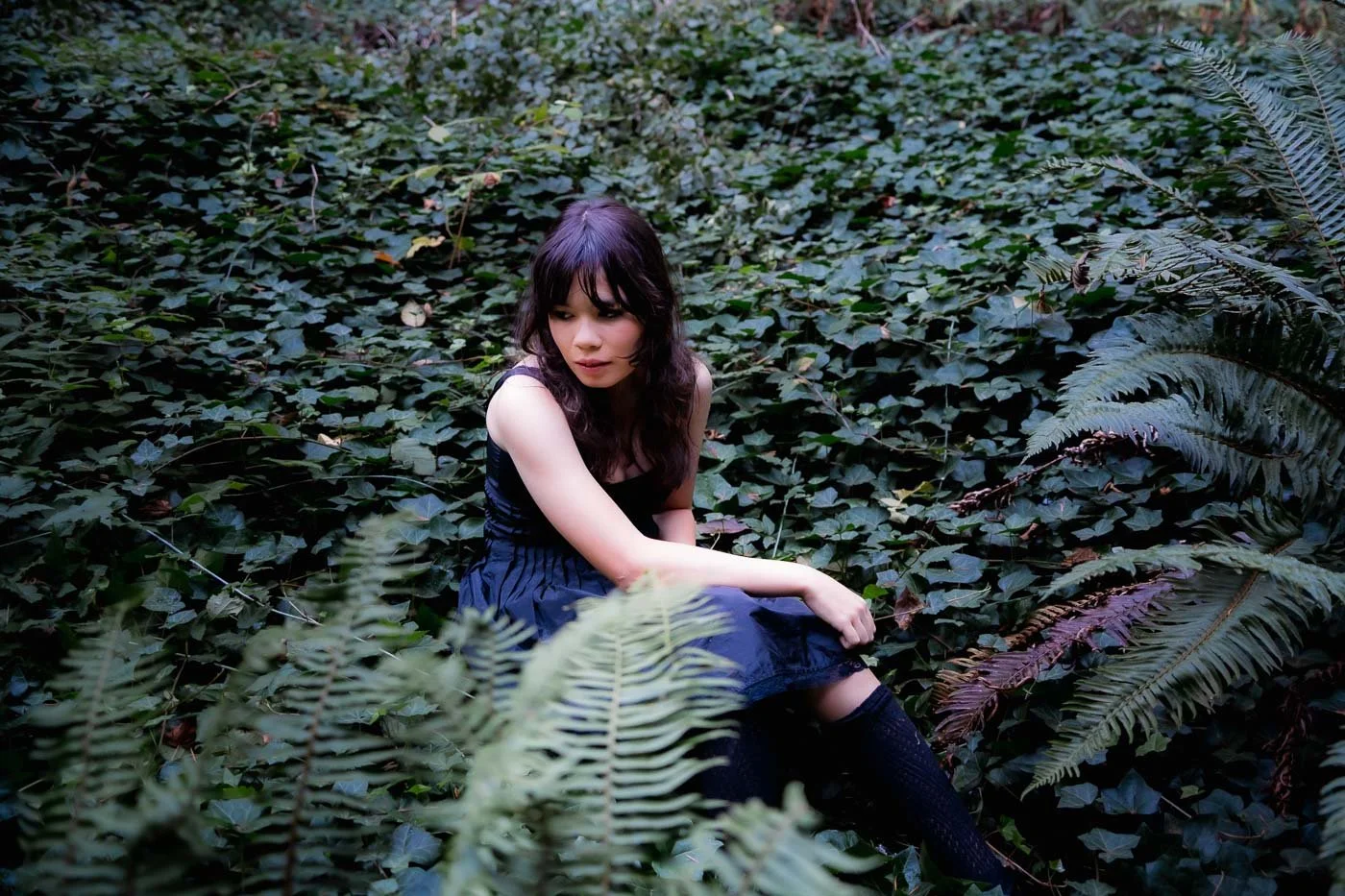 High school senior poses in Forest Park surrounded by ferns and ivy