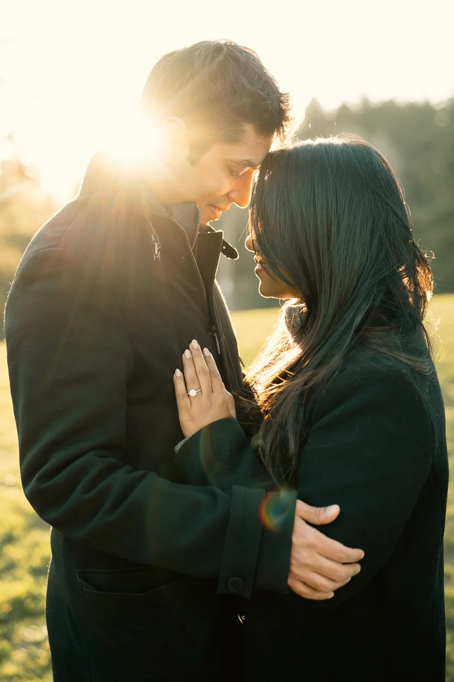 An indian couple embraces with the sun behind them