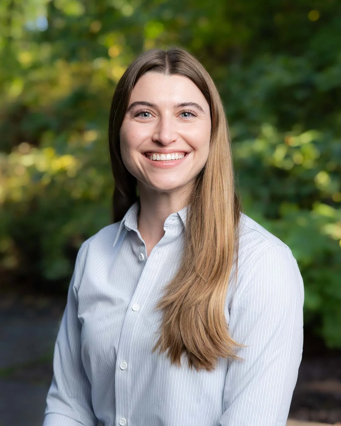 Outdoor headshot of a woman with long brown hair