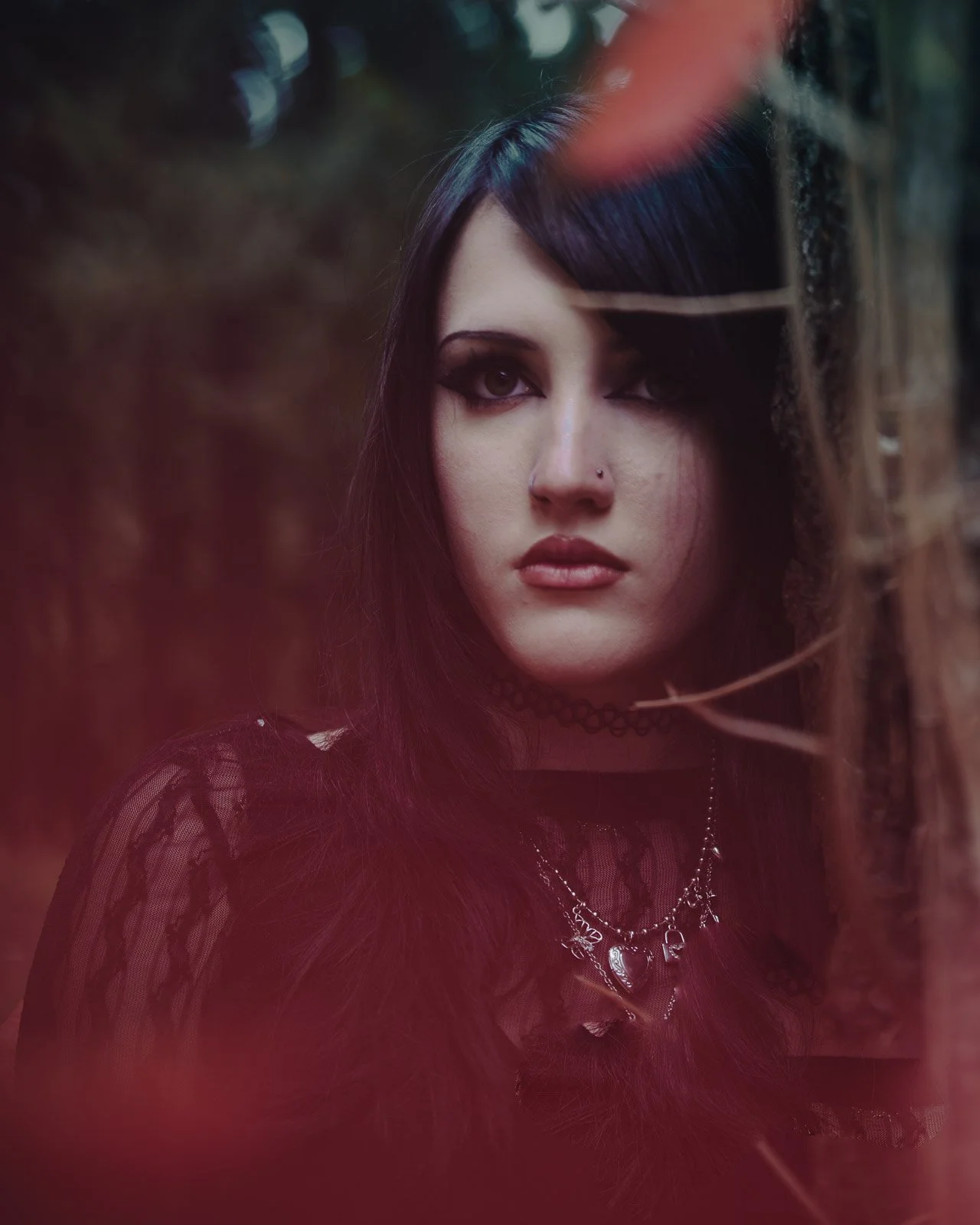 Close up portrait with red bokeh of a high school senior in all black