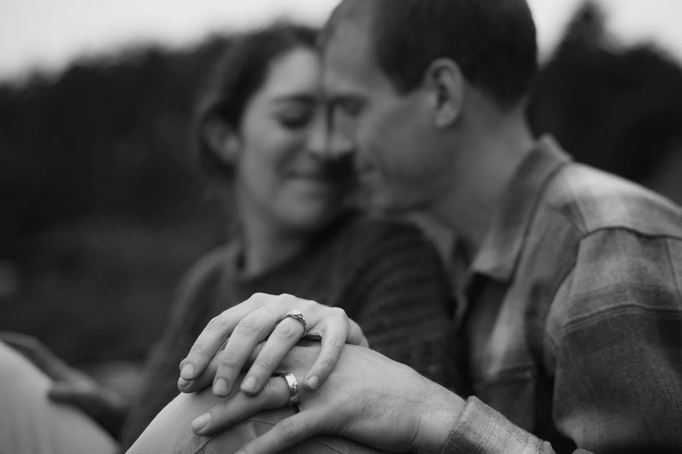 An engaged couple holding hands and touching their faces together 