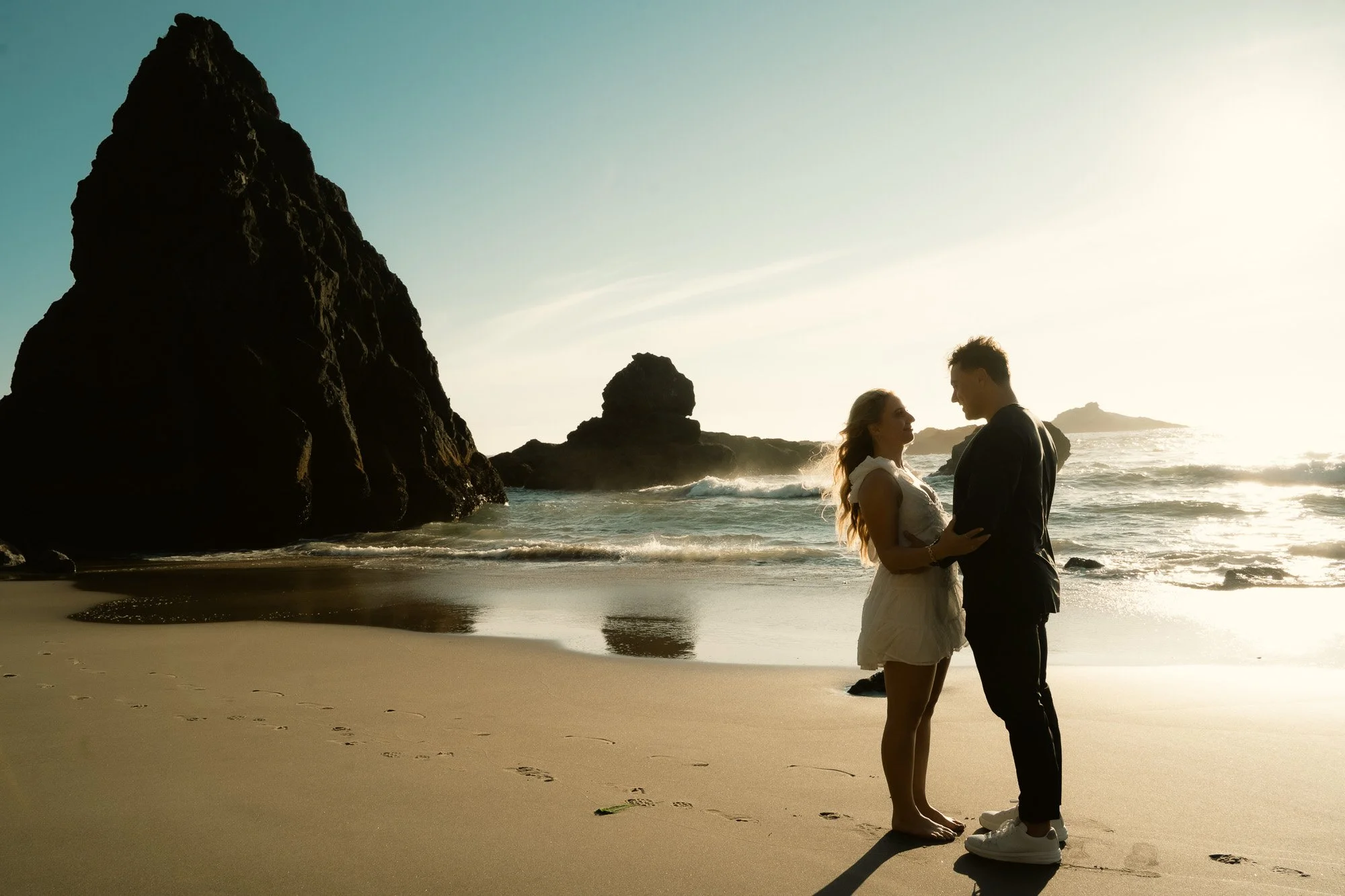 Golden hour beach engagement photos of a couple holding each other