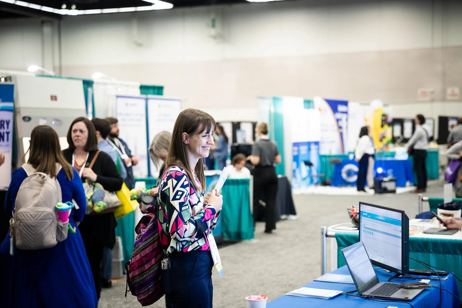A smiling woman in front of a booth at a medical conference