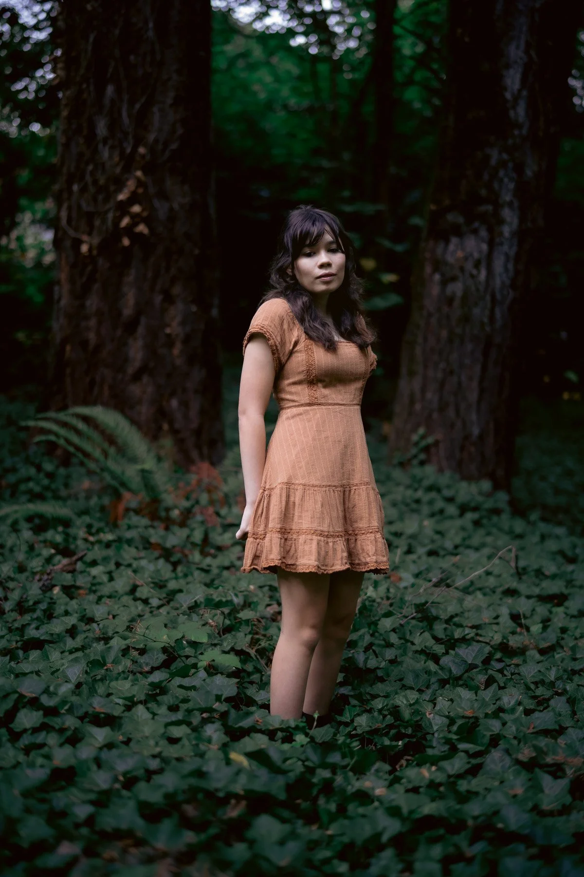 Moody portrait of a girl standing in a dense forest