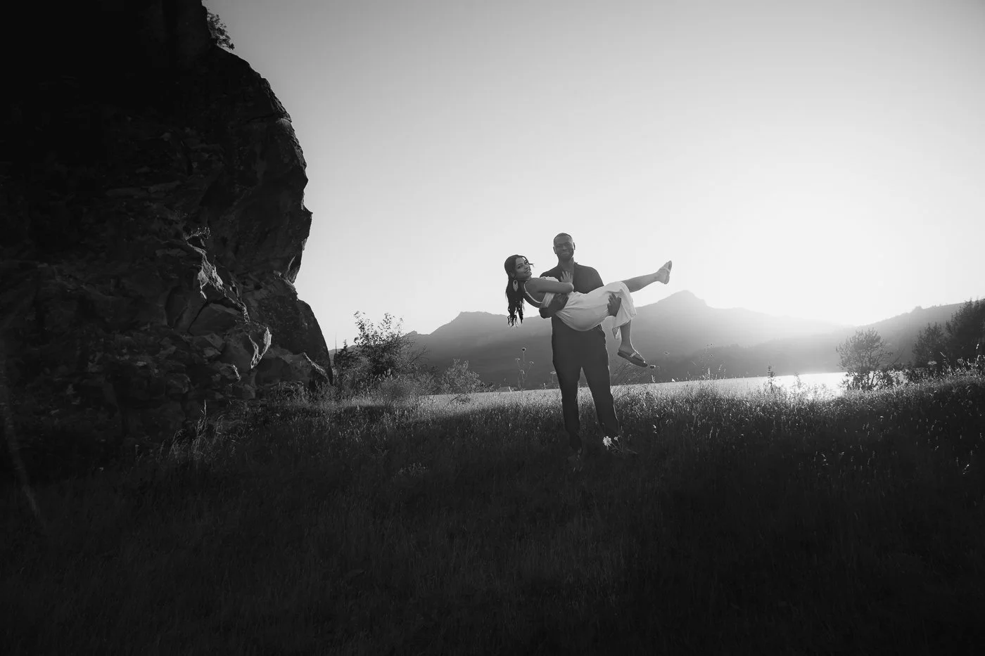 A man picks up his fiance with the columbia river in the background