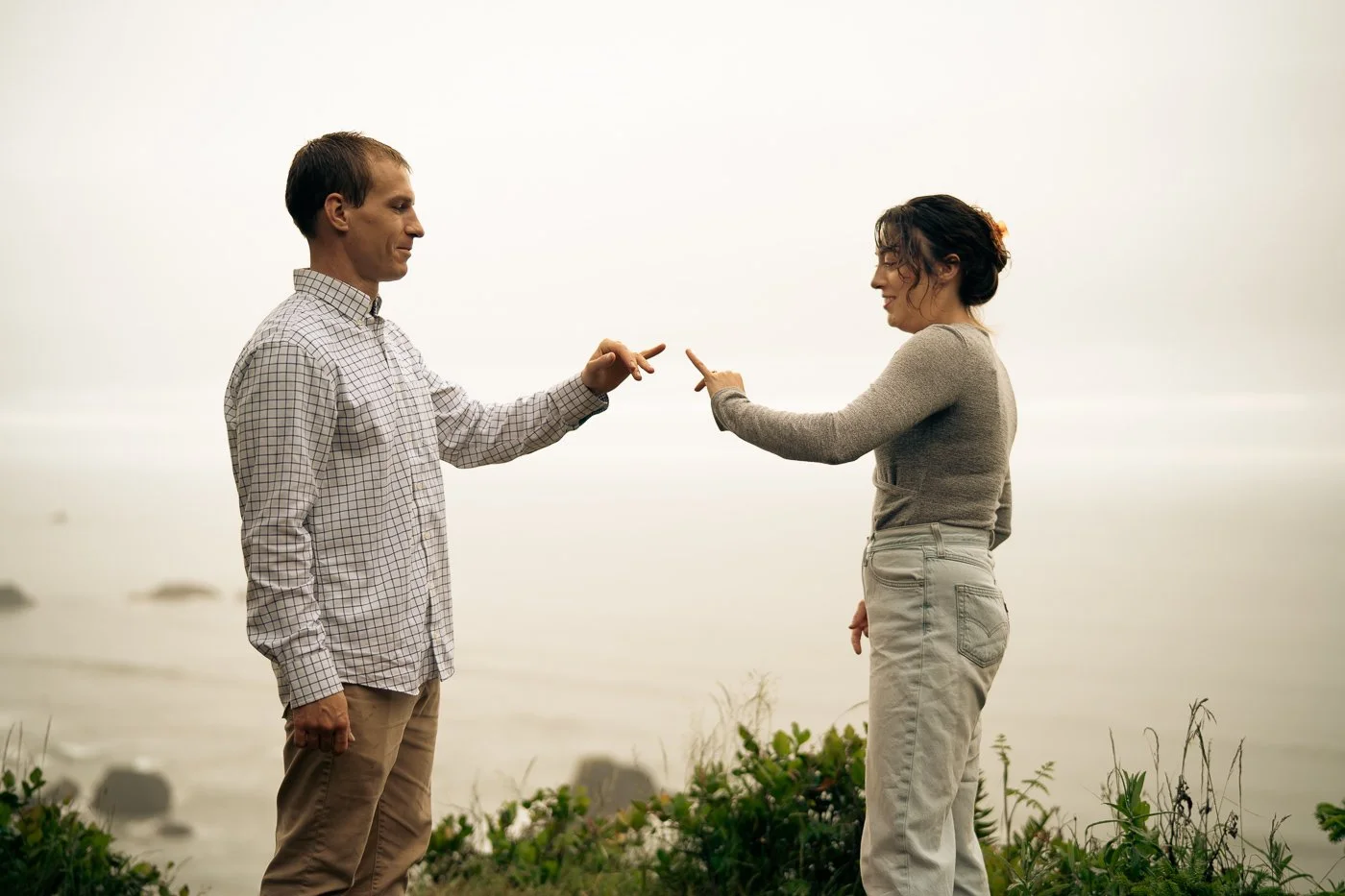 A couple holding out their hands for a pinky promise, on the cliffs above Indian Beach