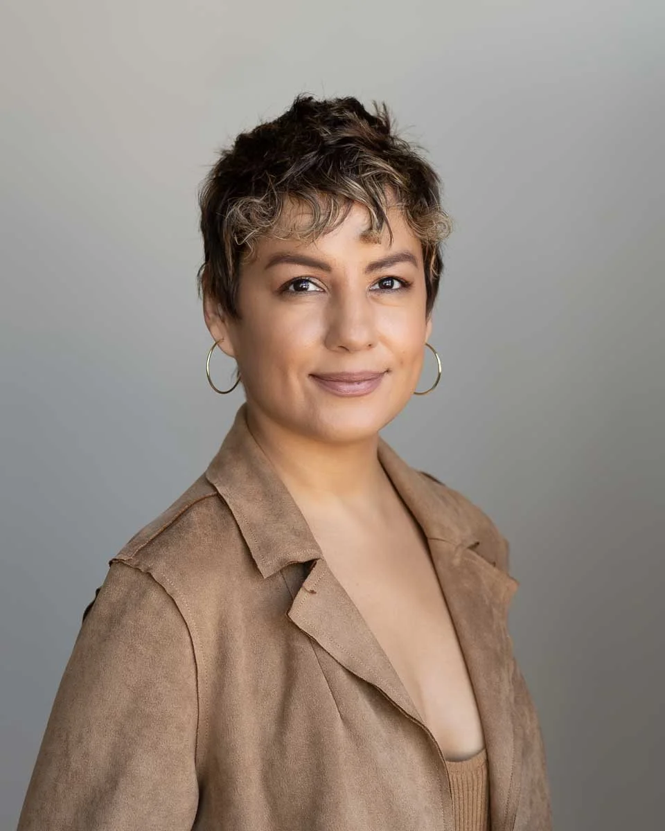 Headshot of a stylish woman in a matching tan shirt and jacket