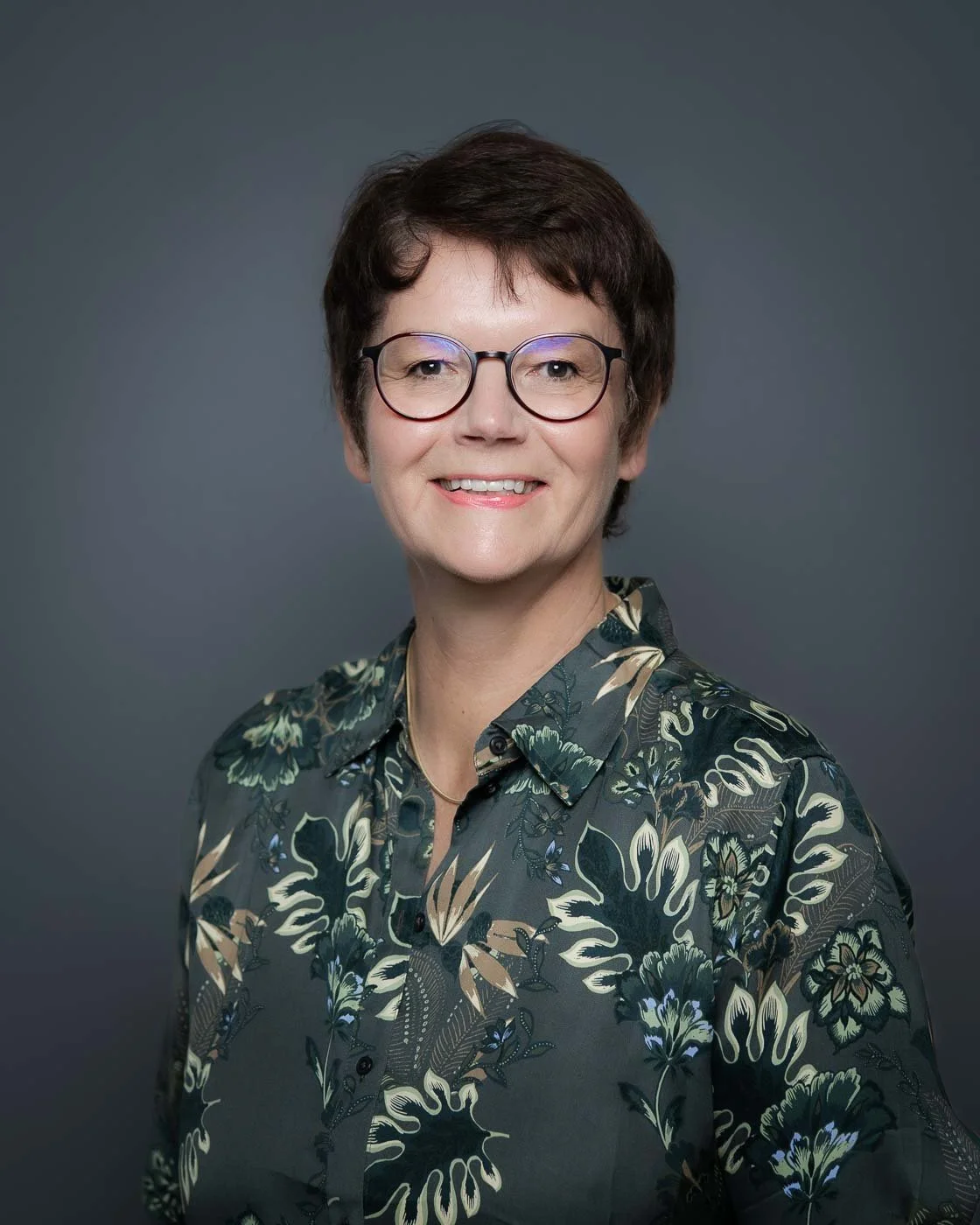 Headshot with flash, of a woman in a patterned green shirt
