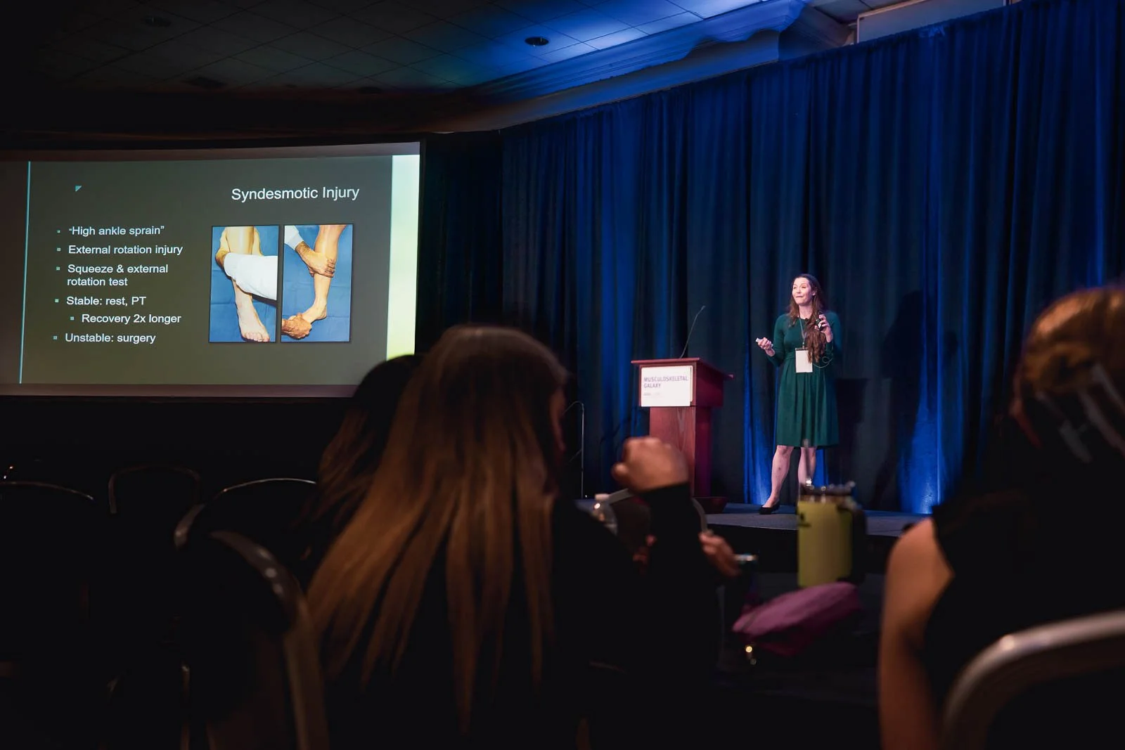 A woman delivers a medical presentation on a large stage