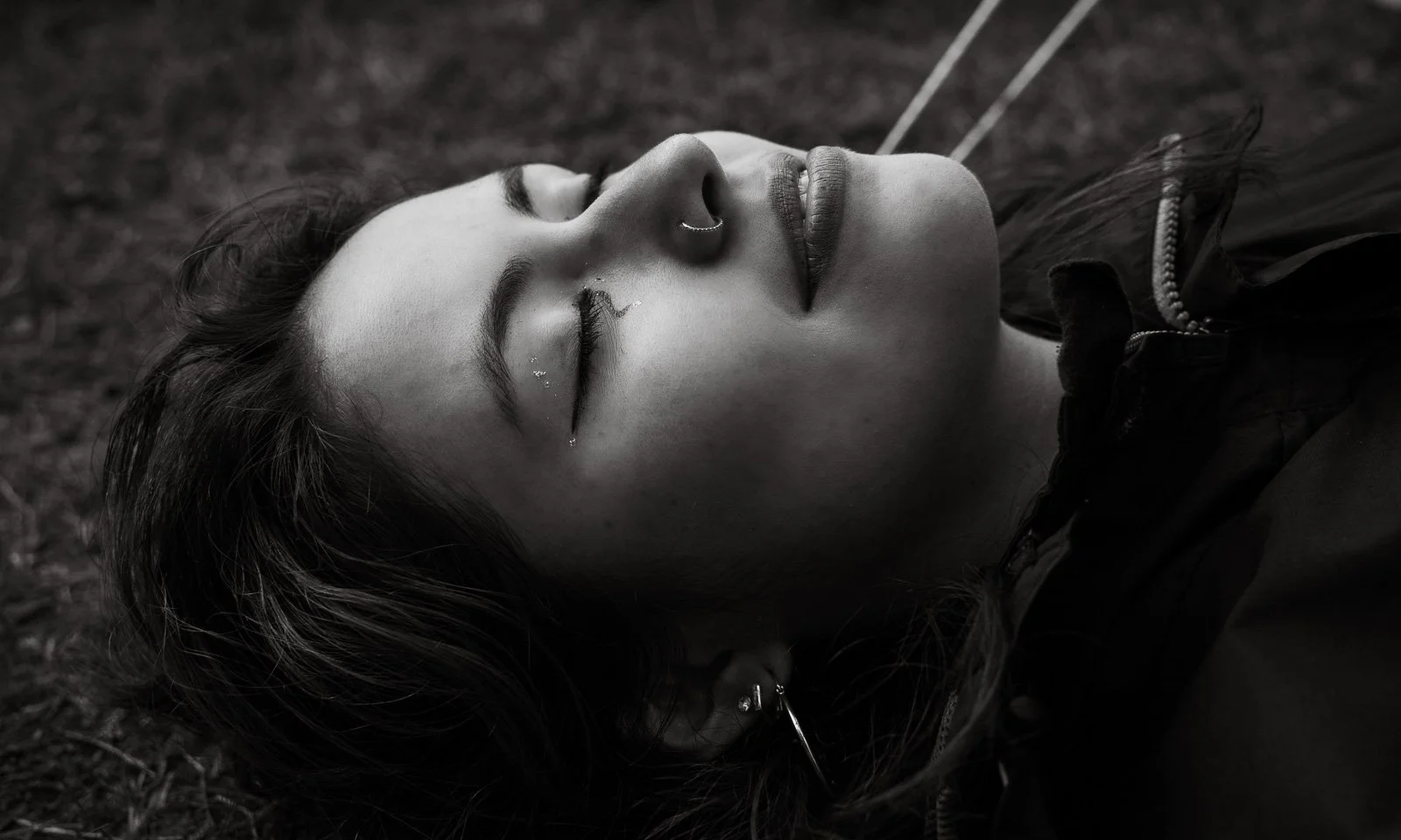 A young girl with unique eye makeup lays on the ground with her eyes closed