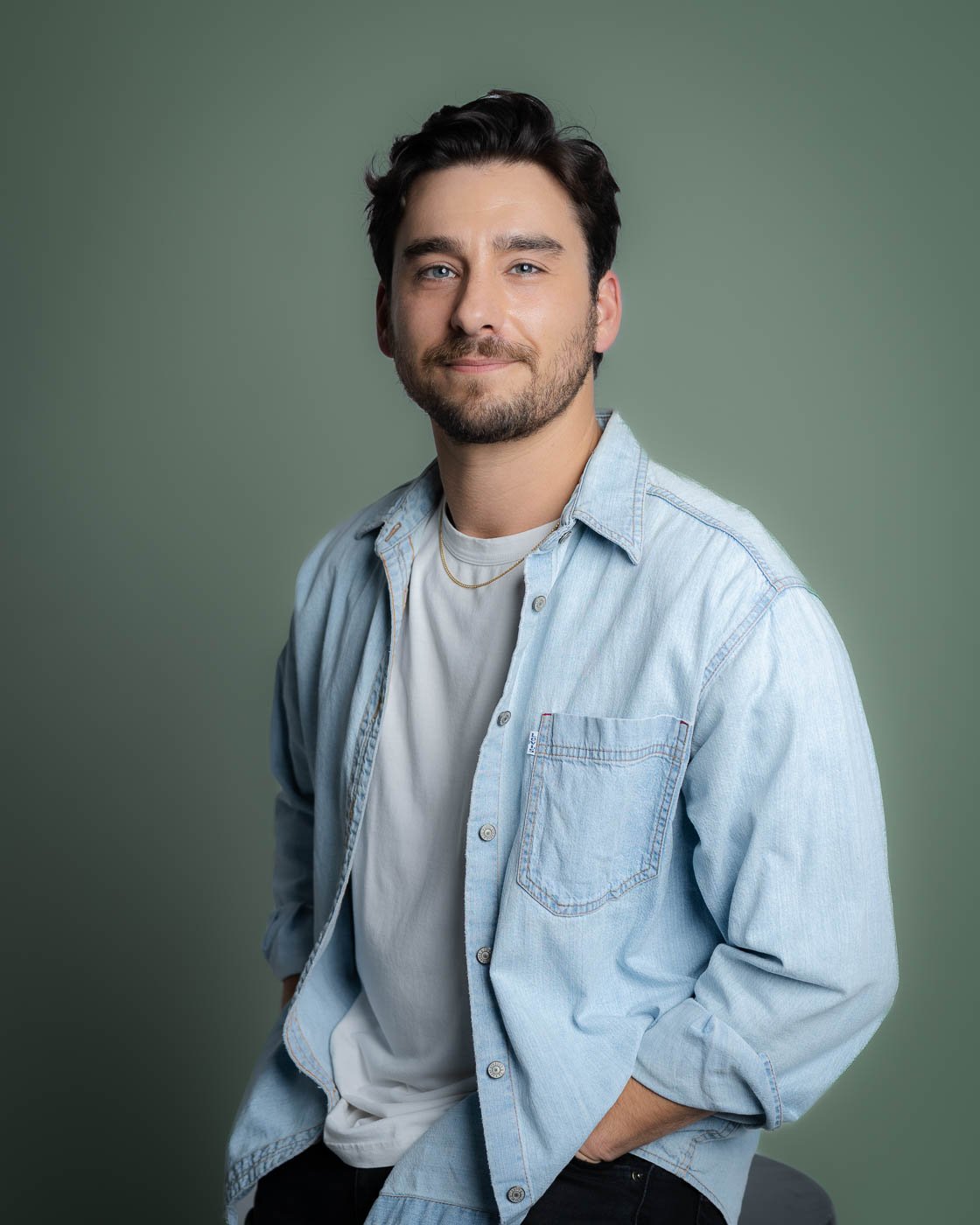 Editorial style headshot of a man in a blue denim shirt