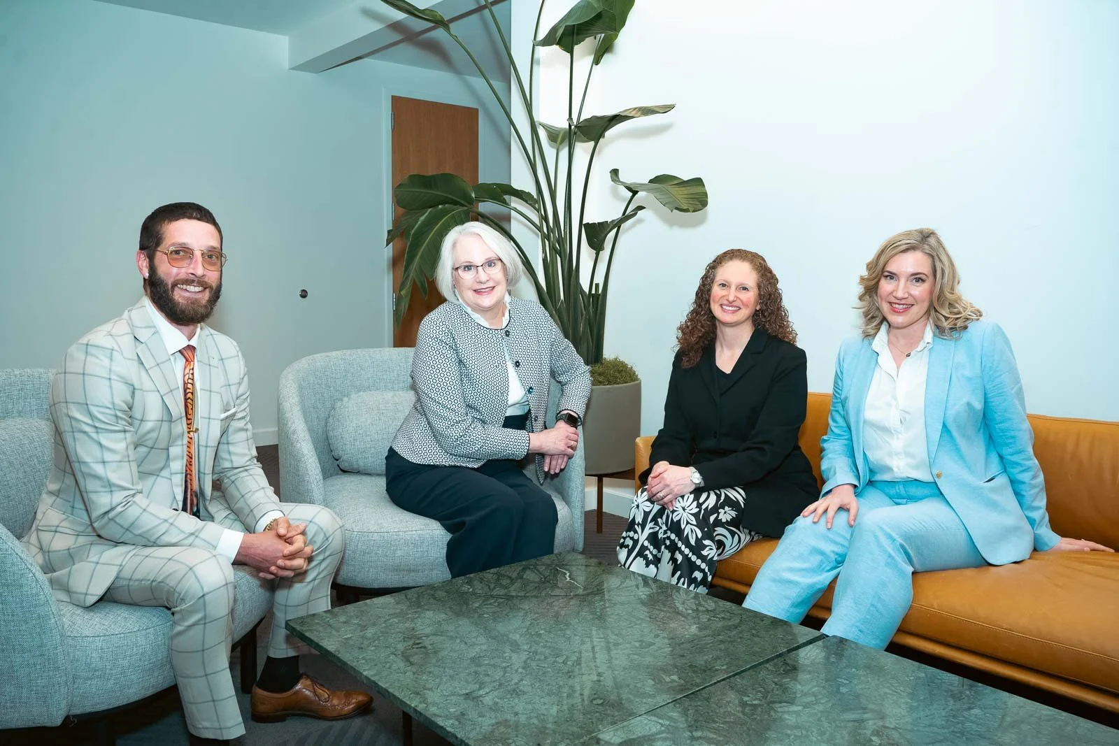 Four smiling people in business wear sitting on sofas