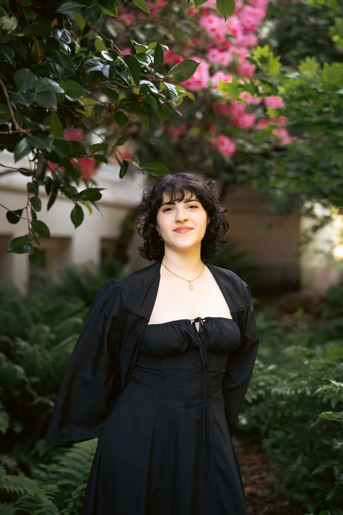 Graduation photos for a young girl in a black dress surrounded by pink flowers