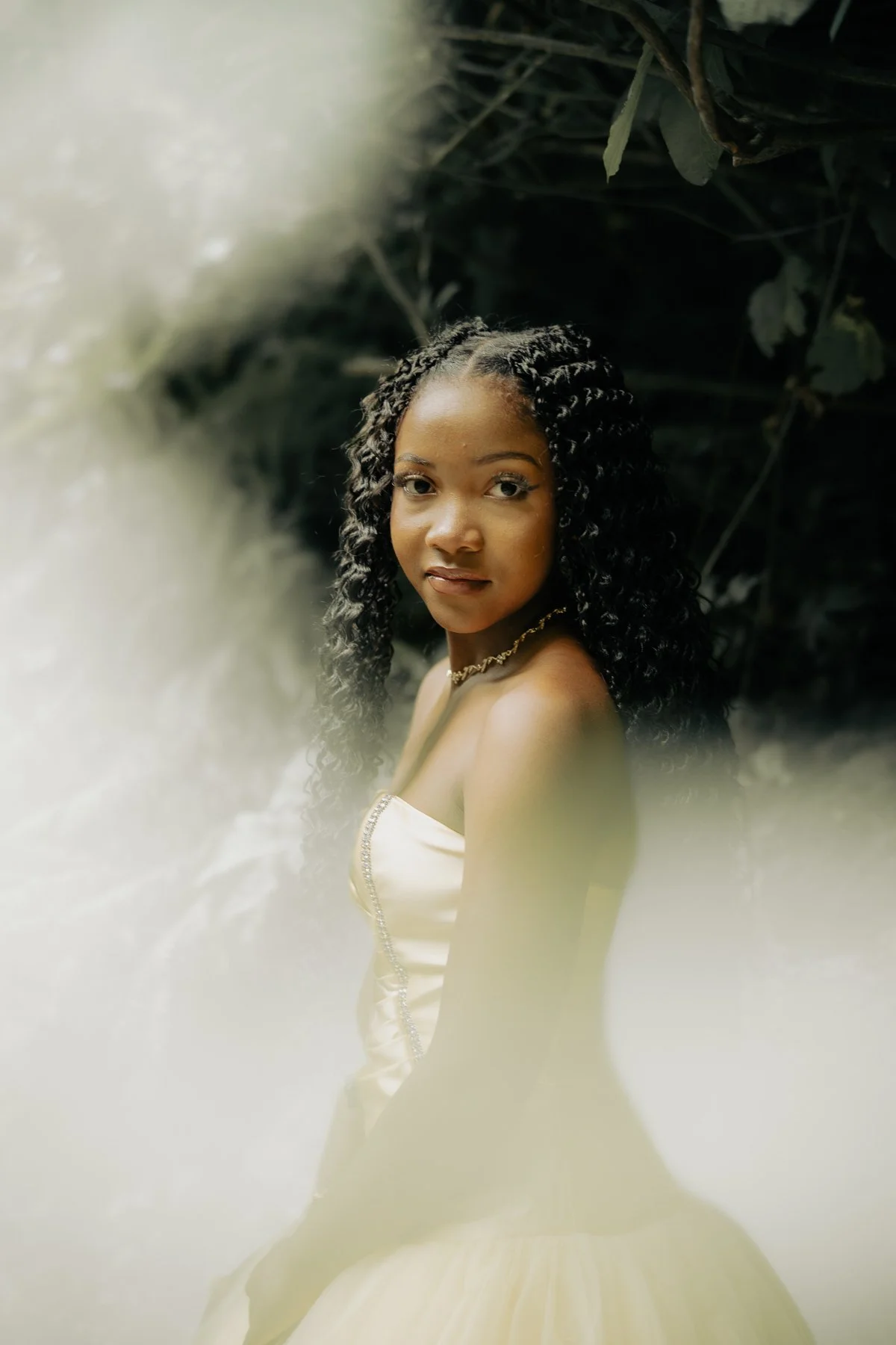 A young black girl in a rose colored dress surrounded by blurred nature
