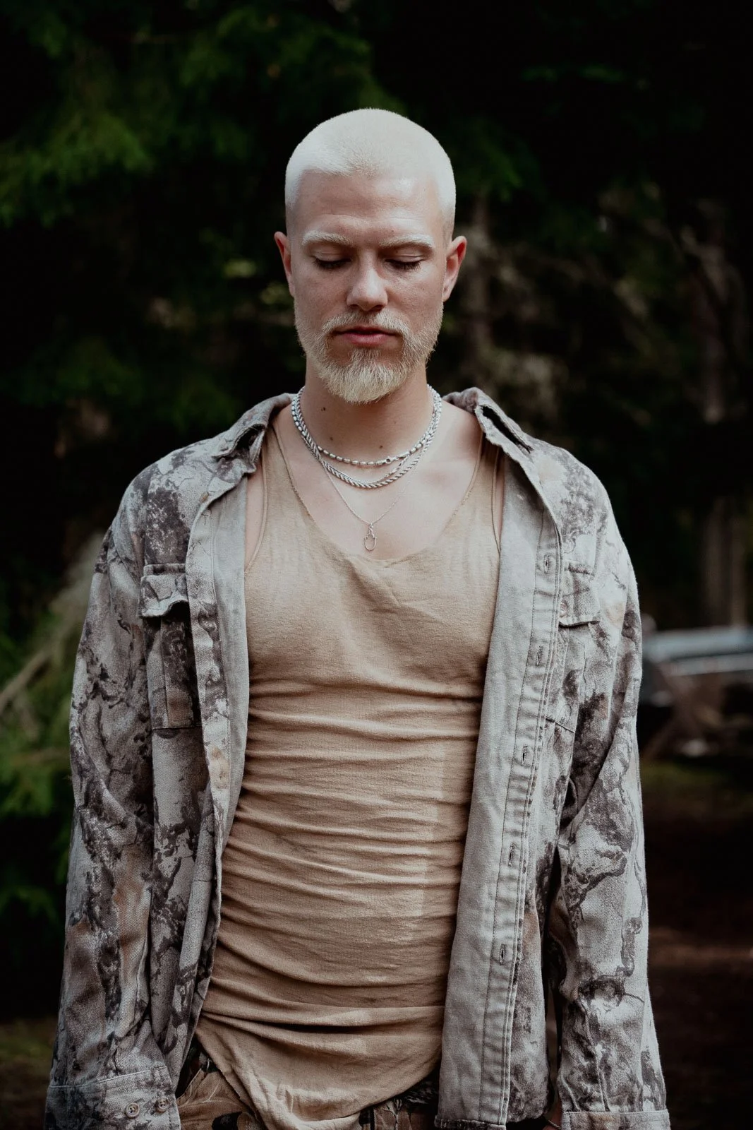 Musician portrait standing with his eyes closed and the forest behind him