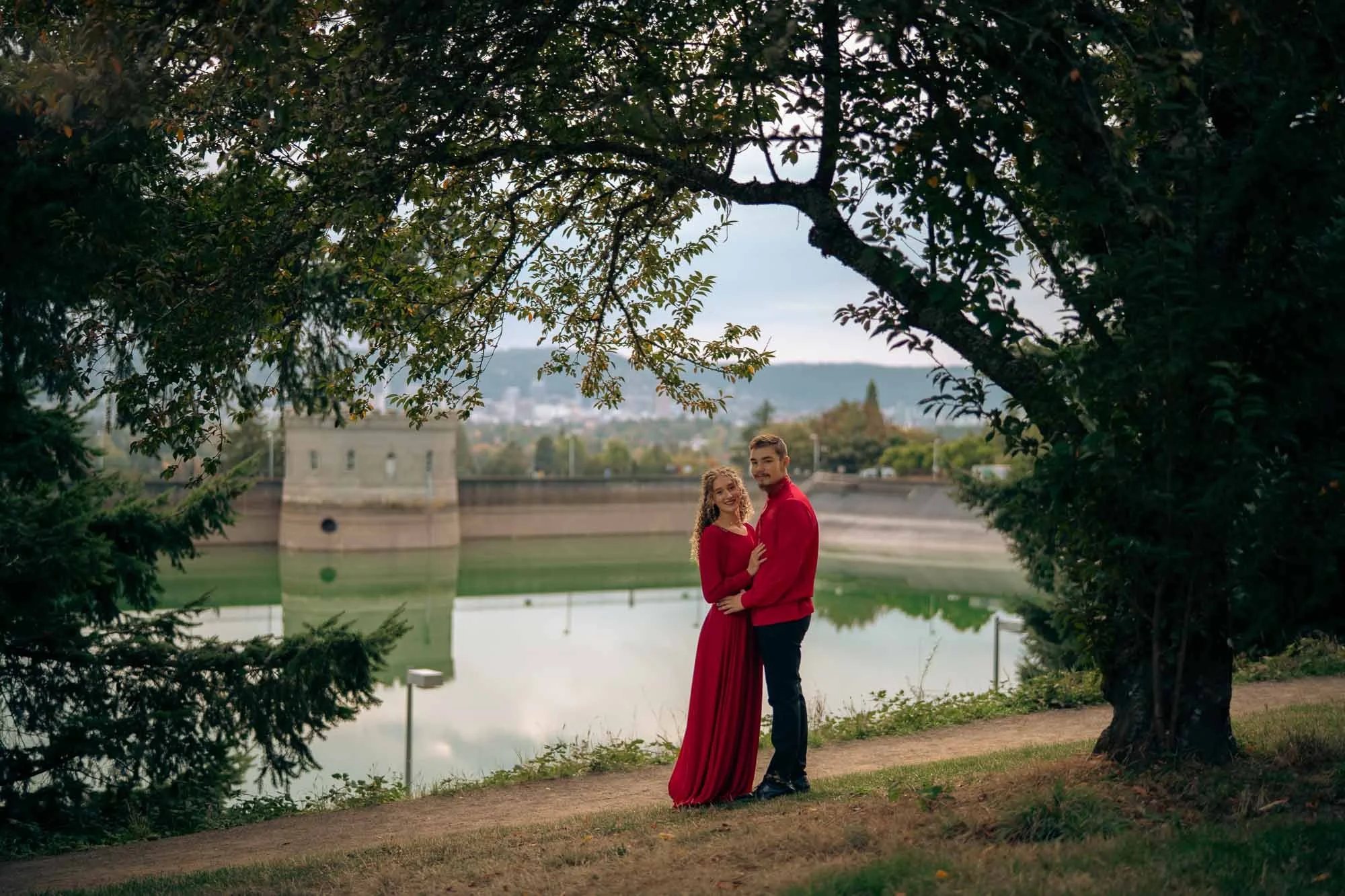 A smiling couple in matching red in front of the water reservoir at Mt Tabor