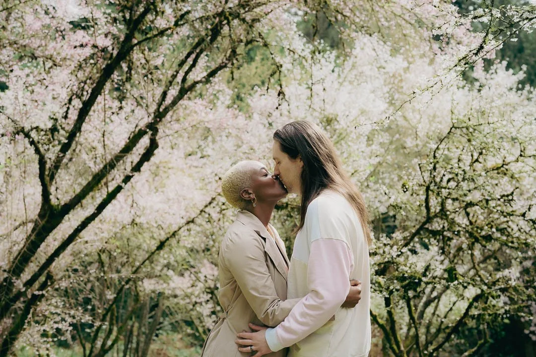 A couple kissing amongst cherry blossom trees