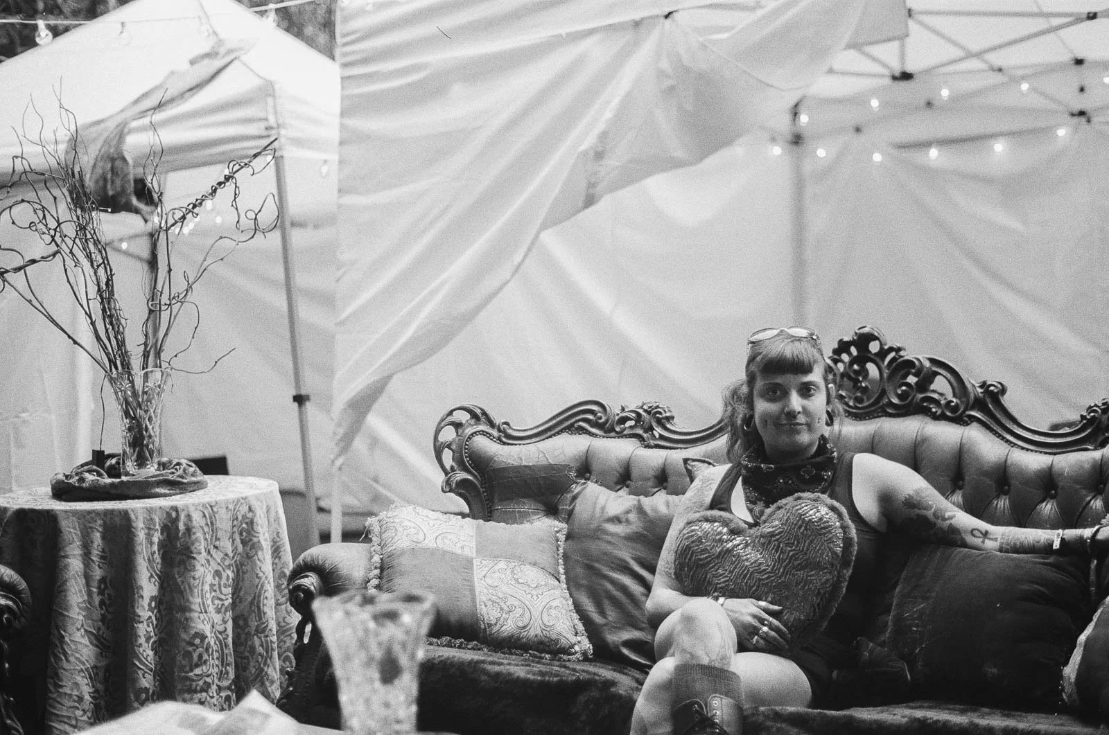 A smiling girl sits on a couch in a room decorated to look victorian 