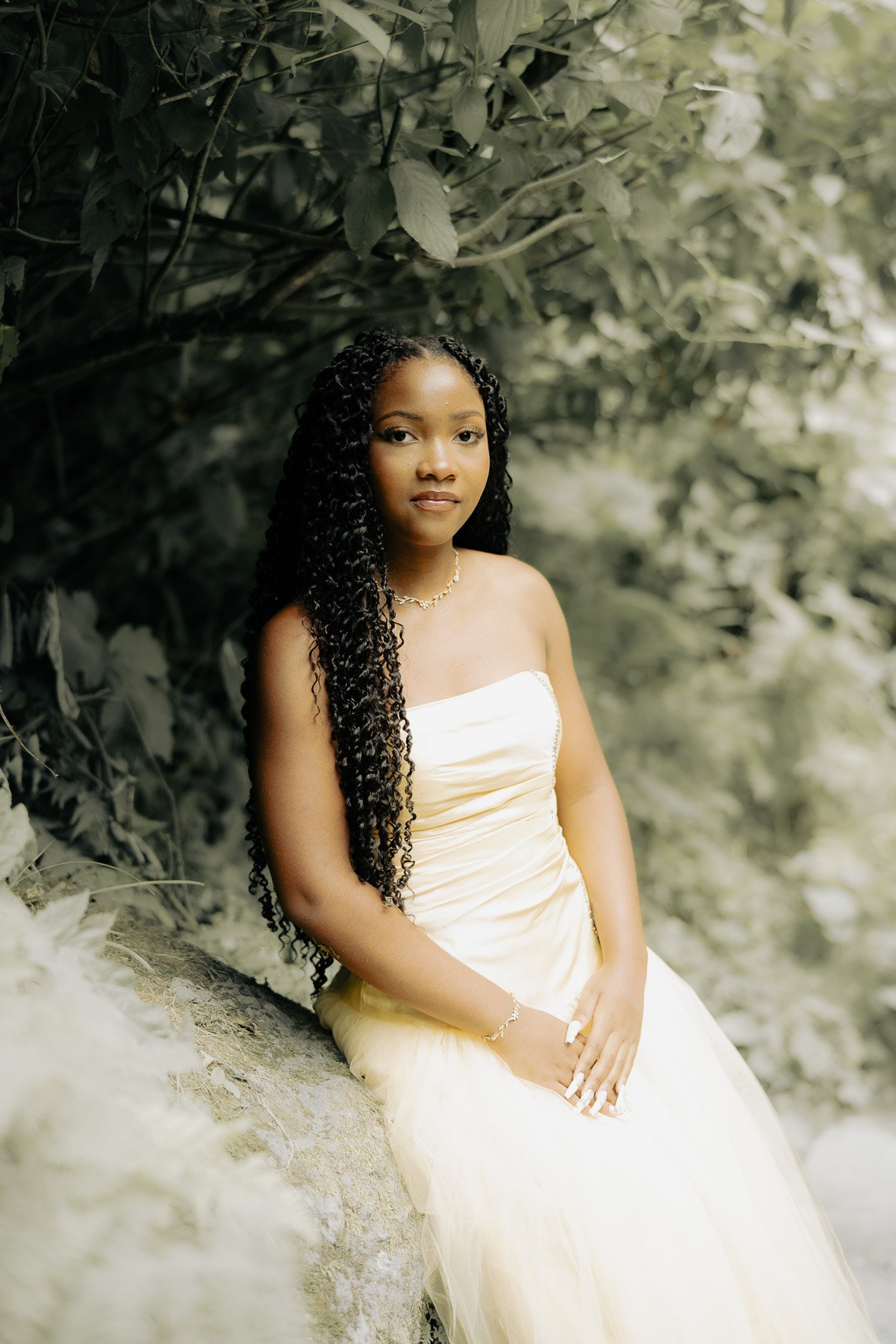 Elegant portrait of a girl in a rose dress leaning on a rock