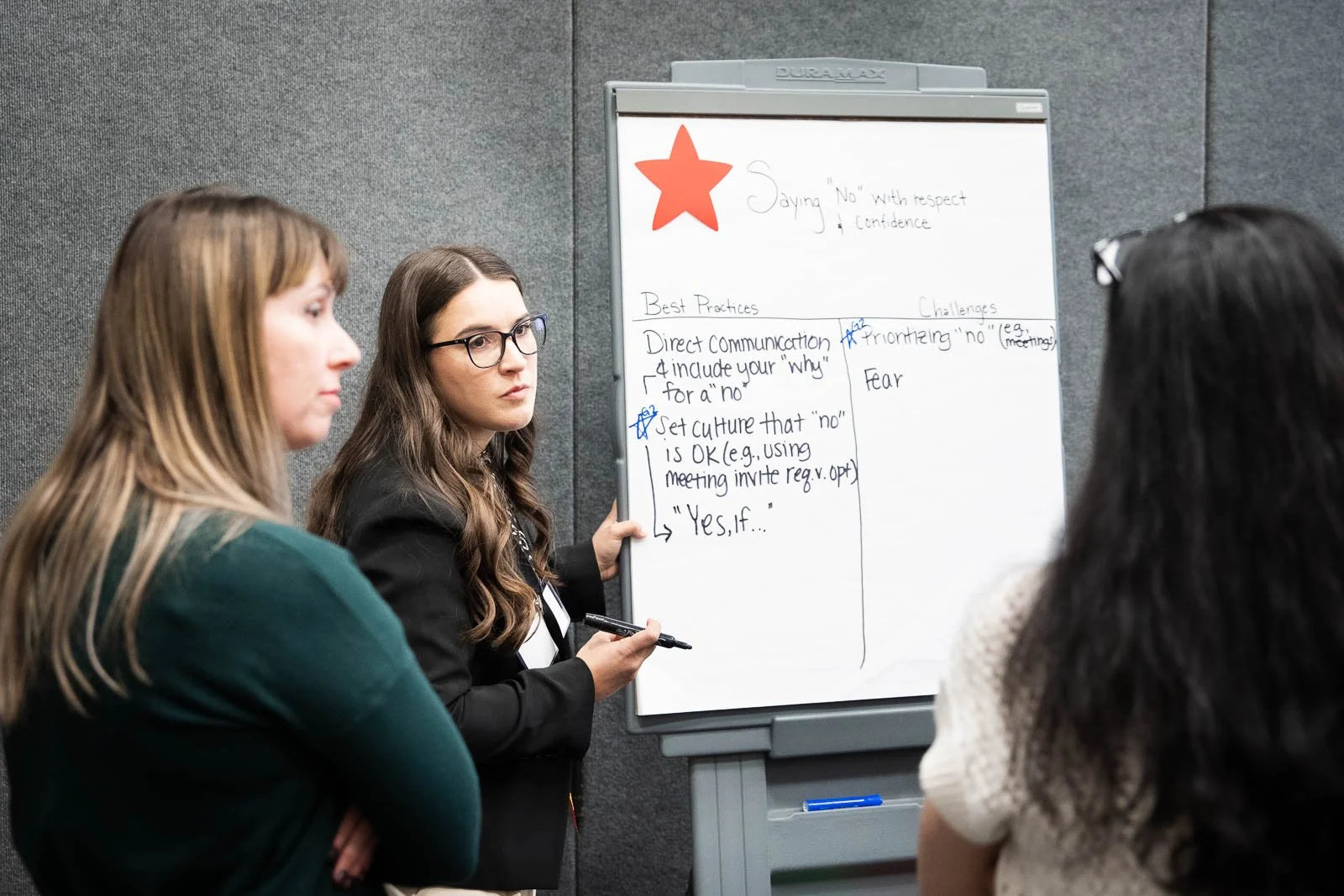 Three women stand around a whiteboard during a medical workshop
