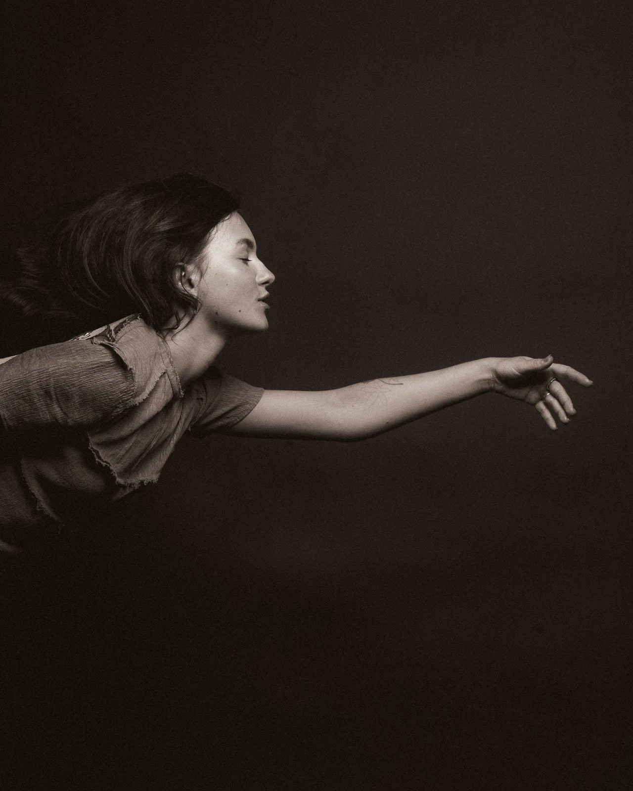 A girl with her arm stretched out, seeming to fly