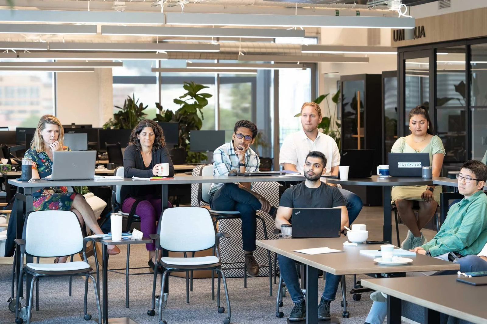 Attentive Gridstor employees with laptops at a work meeting in Portland